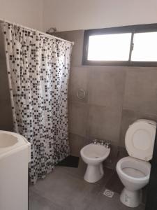 a bathroom with a toilet and a shower curtain at La Tranquera 2 in La Paz +2 photos