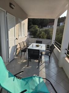 a patio with a table and chairs on a balcony at Mala Basina -Maslina in Vrbanj