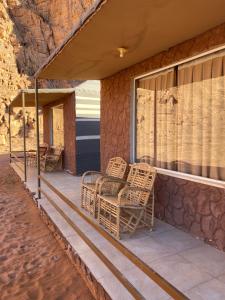 a porch with two wicker chairs and a window at Milano Rum Luxury Camp in Wadi Rum