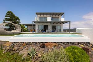 una casa con piscina di fronte a una casa di Villa Reflejo de Mar a Cotillo
