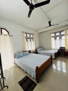 a bedroom with two beds and a ceiling fan at Sanjukta Homestay in Nowgong