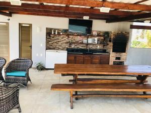 a patio with a wooden table and chairs and a kitchen at Paraíso em Flecheiras in Trairi