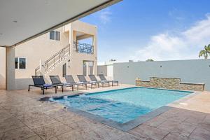 a swimming pool with chairs and a house at Aruba Comfort Retreat 2br W Pool, Bbq & Gated in Pos Abao
