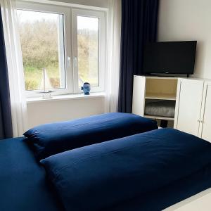 a bedroom with a blue bed and a window at Ferienwohnung Wulf Sylt EG in Wenningstedt