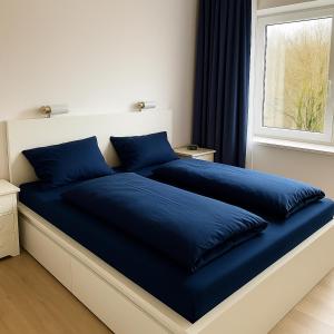 a bed with blue pillows on it in a bedroom at Ferienwohnung Wulf Sylt EG in Wenningstedt