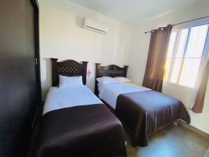 two beds in a room with a window at Casa 3 Bugambilia de Villa Verde in Chiquimula