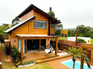 a house with a deck and a swimming pool at Casa com Banheira, Piscina e Quadra de Areia in Praia do Rosa