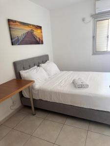 a bed in a room with a table and a picture on the wall at מגדלי חי 3 in Eilat +4 photos