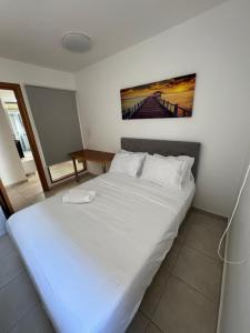 a bedroom with a white bed with a picture on the wall at מגדלי חי 3 in Eilat