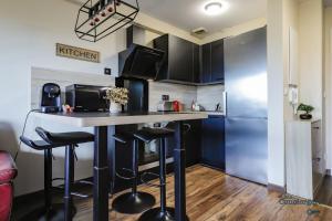 eine Küche mit einer Bar mit Hockern und einem Kühlschrank in der Unterkunft Montaigne - Proche Tram - 5min Aéroport in Blagnac + 17 Fotos