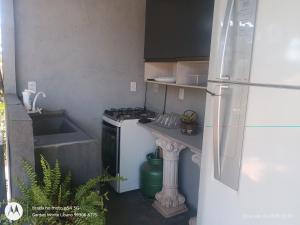 a small kitchen with a refrigerator and a sink at Flat no Garden II in Rondonópolis