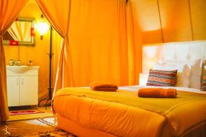 Un dormitorio con una cama con toallas. en Dounia Luxury Camp, en Merzouga