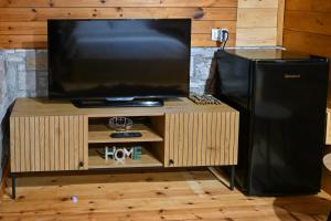 a flat screen tv on a stand with a black refrigerator at Airport Comfort Nest in Kamëz