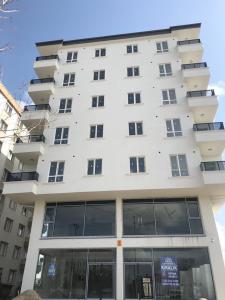 een hoog wit gebouw met ramen ervoor bij Köşk Rezidans 