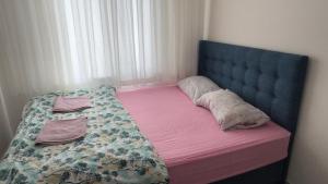 een bed met een blauw hoofdeinde en een roze deken bij Köşk Rezidans 
