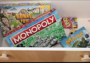 a shelf filled with monopoly and other games at Les terrasses du golf in Égat