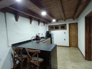 a kitchen with a black counter and two chairs at Cabañas el tigre in Mazamitla
