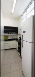 a white kitchen with a refrigerator and a stove at Apartamento 2 suítes Pitangueiras Guarujá in Guarujá