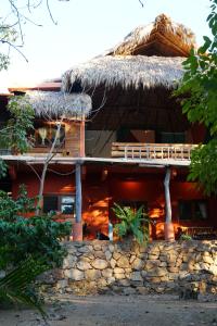 a resort building with a thatched roof and a stone wall at Casita Koru in Zipolite