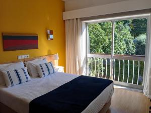 a bedroom with a bed and a large window at Corredoura Garden in Caldelas