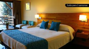 ein Schlafzimmer mit einem großen Bett mit blauen Kissen in der Unterkunft Navidad mágica en Manzano Resort Cabaña completa para 8 personas in Villa La Angostura