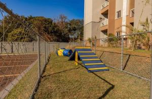 a playground with a slide on a fence at Hospede-se em Barretos Apto 2 Quartos a 600m do Hospital de Amor in Barretos +2 photos