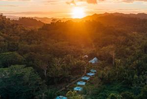 een luchtfoto van een bos met een tent en de zonsondergang bij Jaguar Creek in Good Living Camp