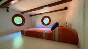 a bed in a small room with two windows at Casita Koru in Zipolite