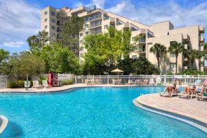 a swimming pool with two people sitting on lounge chairs in front of a building at JS Luxury Vacation in Orlando