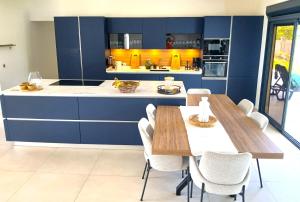 a kitchen with blue cabinets and wooden tables and chairs at B&B chez Momo in Sainte-Anne