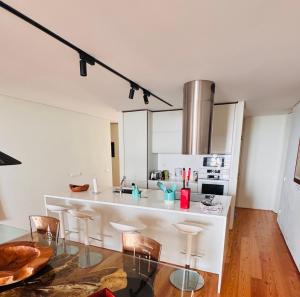 a white kitchen with a glass table and chairs at Luxury House on the Cliff in Trafaria