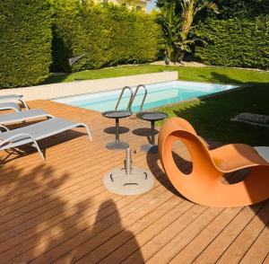 a wooden deck with chairs and a swimming pool at Luxury House on the Cliff in Trafaria