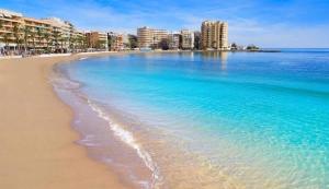 ein Strand mit einer Stadt im Hintergrund in der Unterkunft Casa Feliz in Torrevieja