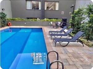 a swimming pool with lounge chairs next to a building at Flat Wyndham2 Paulista com estacionamento in Sao Paulo +35 photos