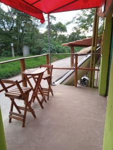 a patio with two chairs and a table and an umbrella at Pousada da Prainha in Mairiporã