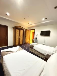 una camera d'albergo con due letti e una TV a schermo piatto di فندق ثمره اليقين a La Mecca