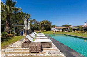 une rangée de chaises longues à côté d'une piscine dans l'établissement Casa Bali Costa brava, à Palafrugell