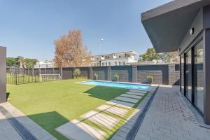 a yard with a swimming pool and a house at Opulent Escape Bryanston in Johannesburg