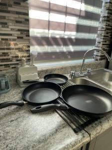 two frying pans on a kitchen counter next to a sink at La Alameda you will feel pampered by the comfort in Nuevo Casas Grandes