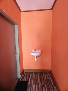 セナルにあるDev Guesthouse and Restaurantのオレンジ色の壁に洗面台があるバスルーム +6枚の写真