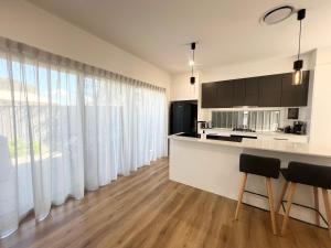 a kitchen with white curtains and a counter with chairs at Seaside Village Retreat in Shellharbour