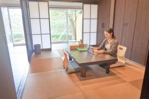 a woman sitting at a table with a laptop at ATAMI SPRING TERRACE HOTEL in Atami