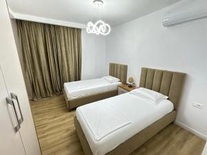 a hotel room with two beds and a chandelier at Amea Apartments in Durrës