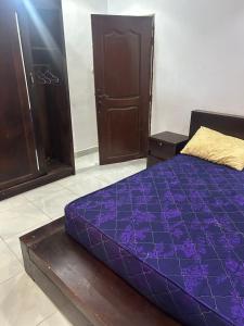 Una cama morada en una habitación con un armario. en Appartement meublé, en Lomé