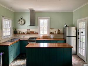 a kitchen with green cabinets and a white refrigerator at Lavender Cottage in Sofala