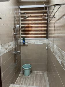 a shower with a blue bucket in a bathroom at CSL Apartments in Madina
