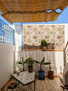a patio with a table and potted plants and a curtain at chambre dans un havre de paix creatif in Essaouira