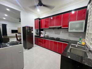 a kitchen with red cabinets and a black refrigerator at Casa De Harmoni in Pasir Puteh