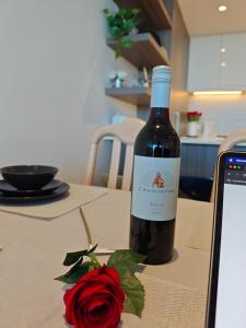 Una botella de vino sobre una mesa junto a una rosa. en Sky High Harbour Bridge View - Sydney Olympic Park, en Sídney