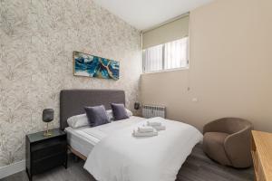 マドリードにあるWaou Glam II Plaza Españaの白いベッドと椅子のある寝室